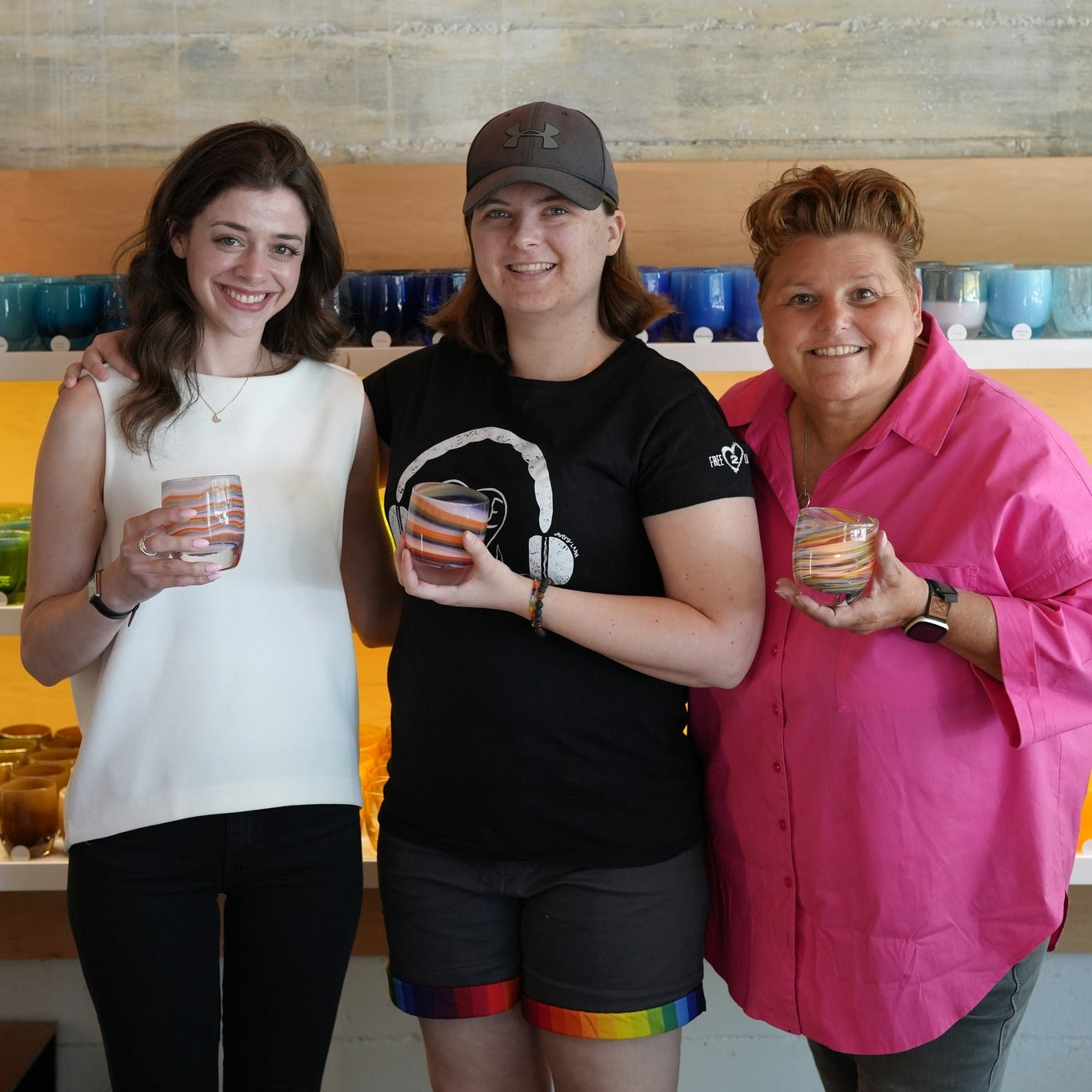 Free2Luv organization representatives with glassybaby employee Maddie each holding a votive in a glassybaby store.