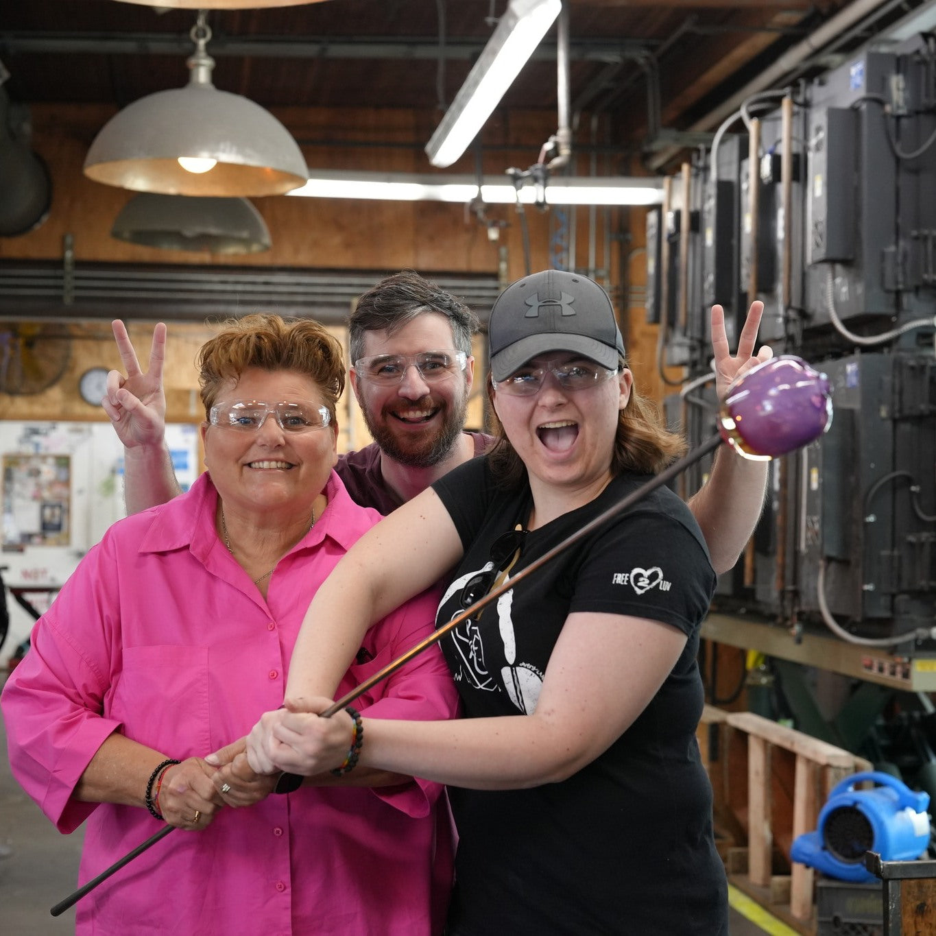 Free2Luv organization representatives with glassblower in a glassybaby hotshop learning and helping in a glass blowing process.