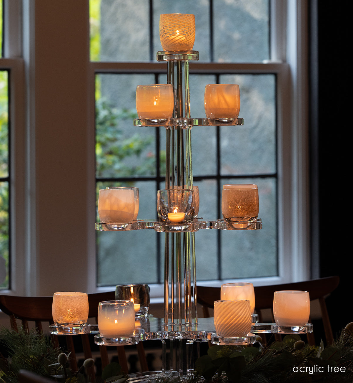 hand-blown glass votive candle holders on acrylic tree stand in front of a window.