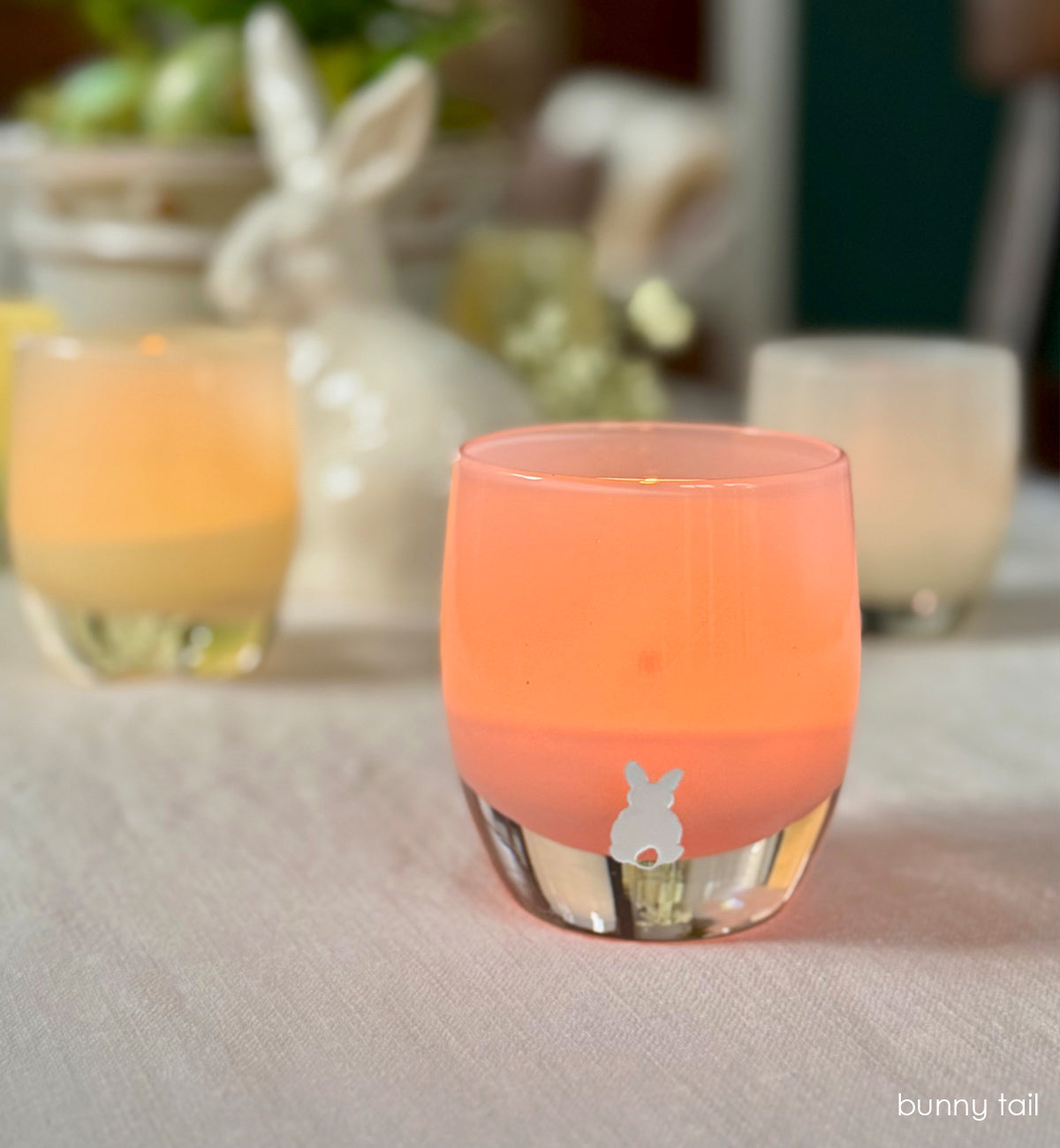 bunny tail - azalea pink hand-blown candle holder with white bunny tail on white table cloth. bunny and glassybaby in background.