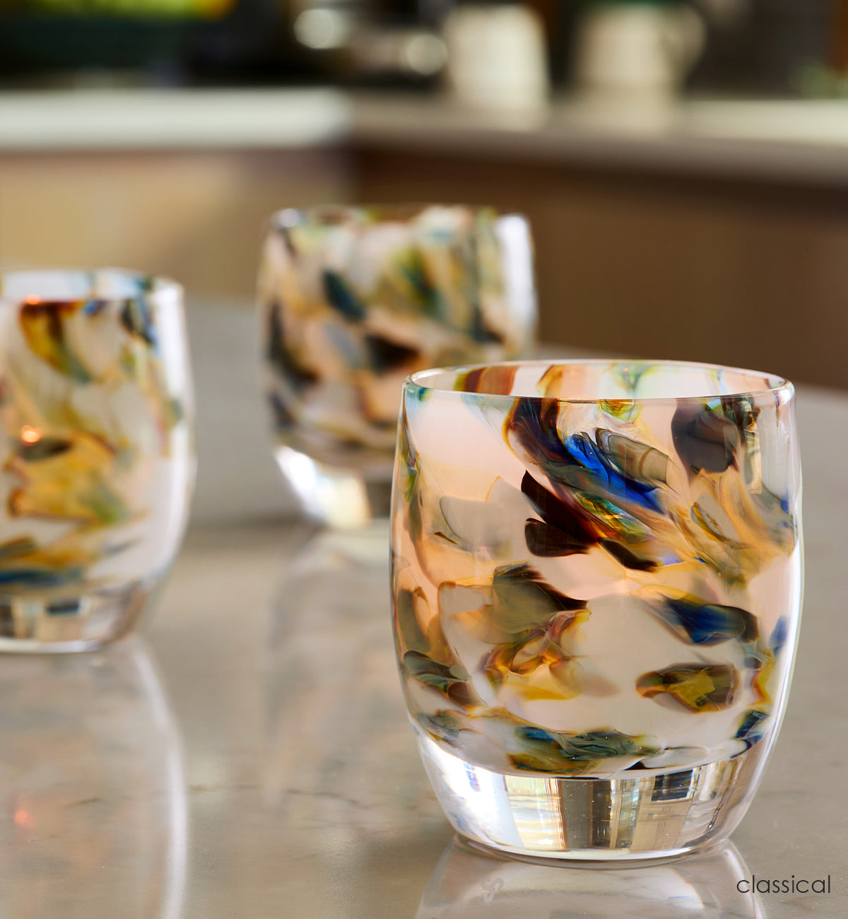 three classical, multi-colored blue marble hand-blown glass votive candle holders on a kitchen island counter.