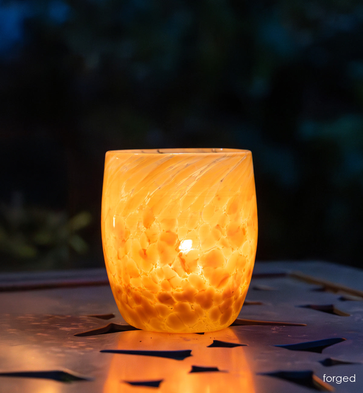 'forged' orange and white hand-blown glass candle holder on metal table 