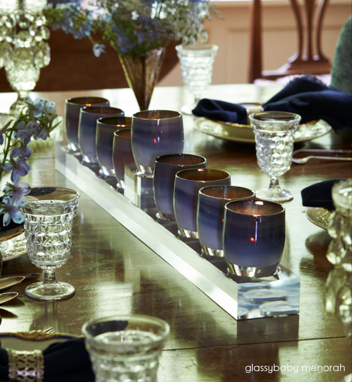 glassybaby menorah with lit mystical on a set dining room table.