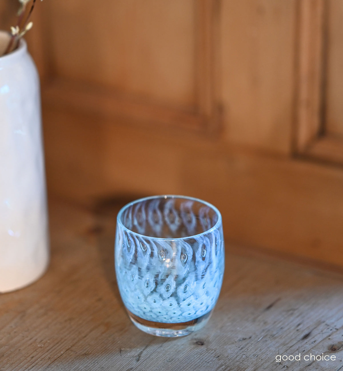 good choice light blue bubble, hand-blown glass votive candle holder on a wood counter.