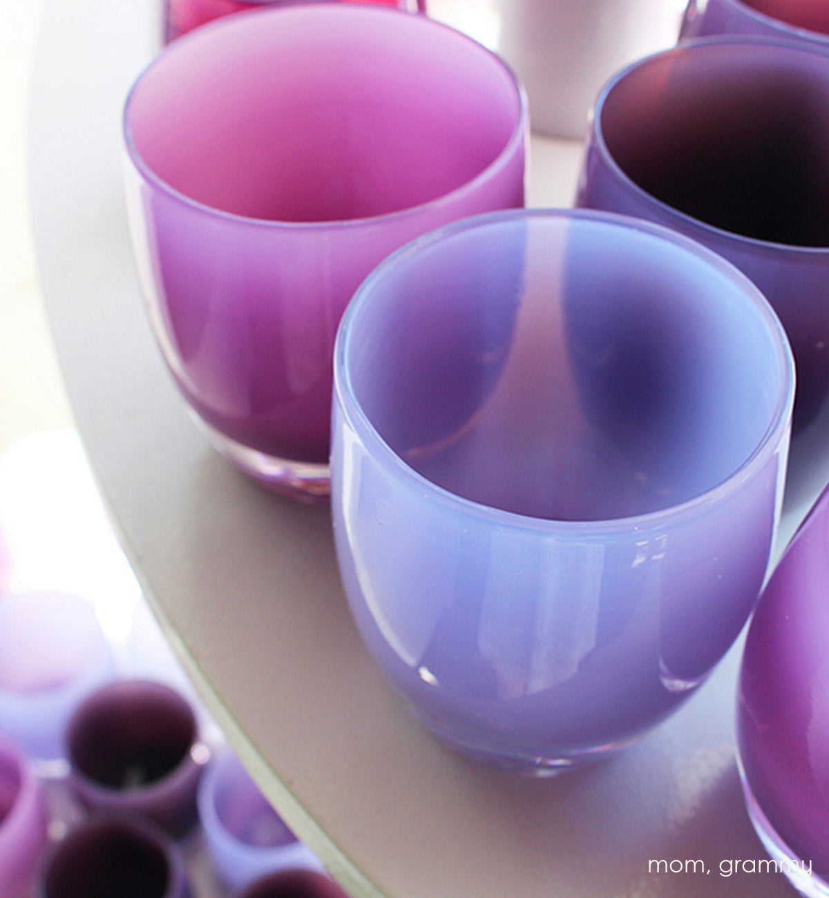 grammy, soft purple hand-blown glass votive candle holder paired in a large grouping with mom on a cream circular table.