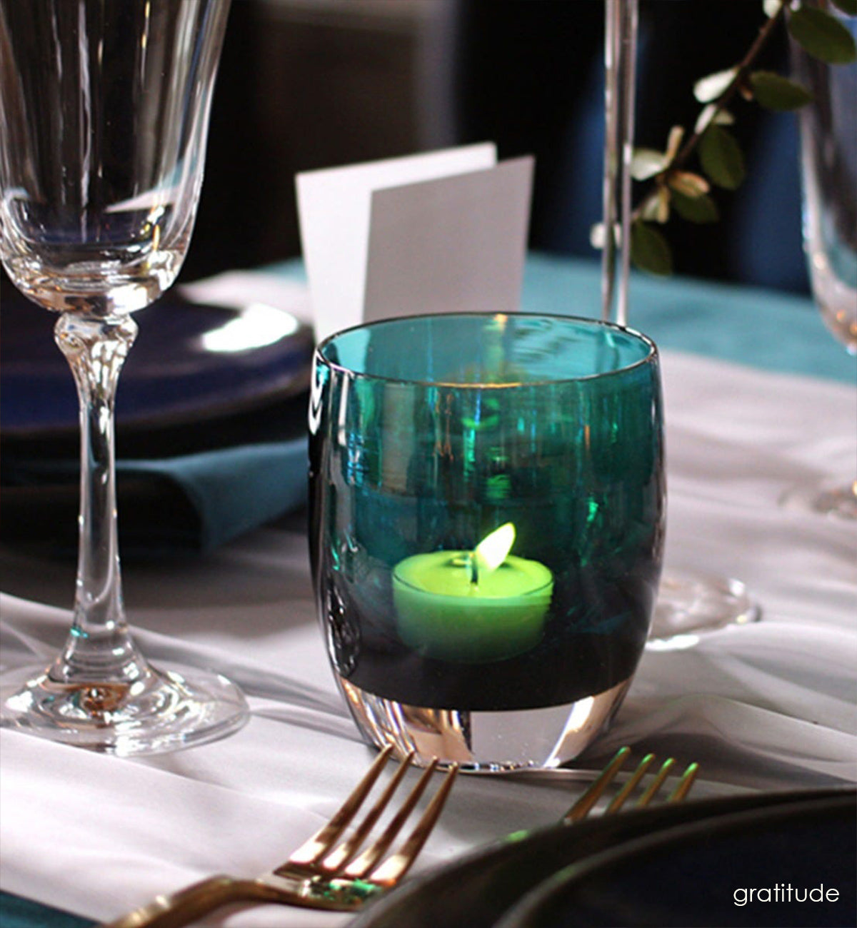 gratitude, textured translucent teal green with silver luster, hand-blown glass votive candle holder presented with dining ware.