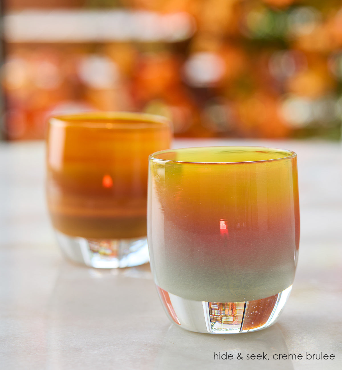 hide and seek autumn tone hand-blown glass votive candle holder on a white marble with creme brulee.