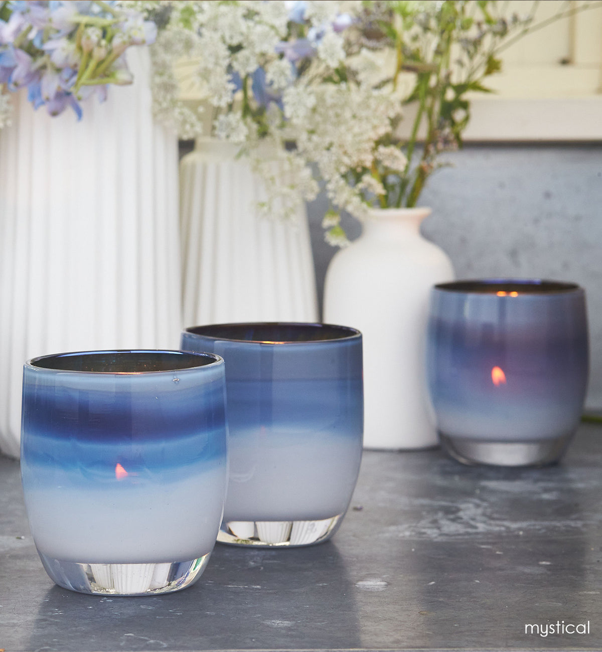 three mystical on a marble surface with white vases filled with flowers.