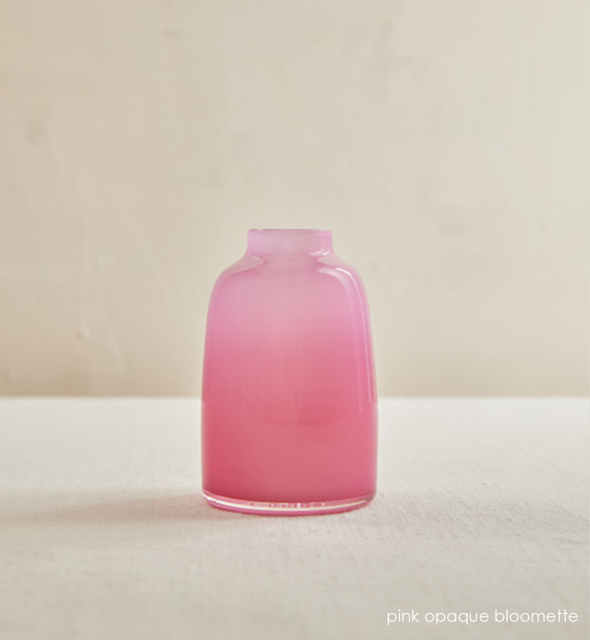 pink opaque bloomette, opaque pink hand-blown glass flower bud vase in front of cream background.