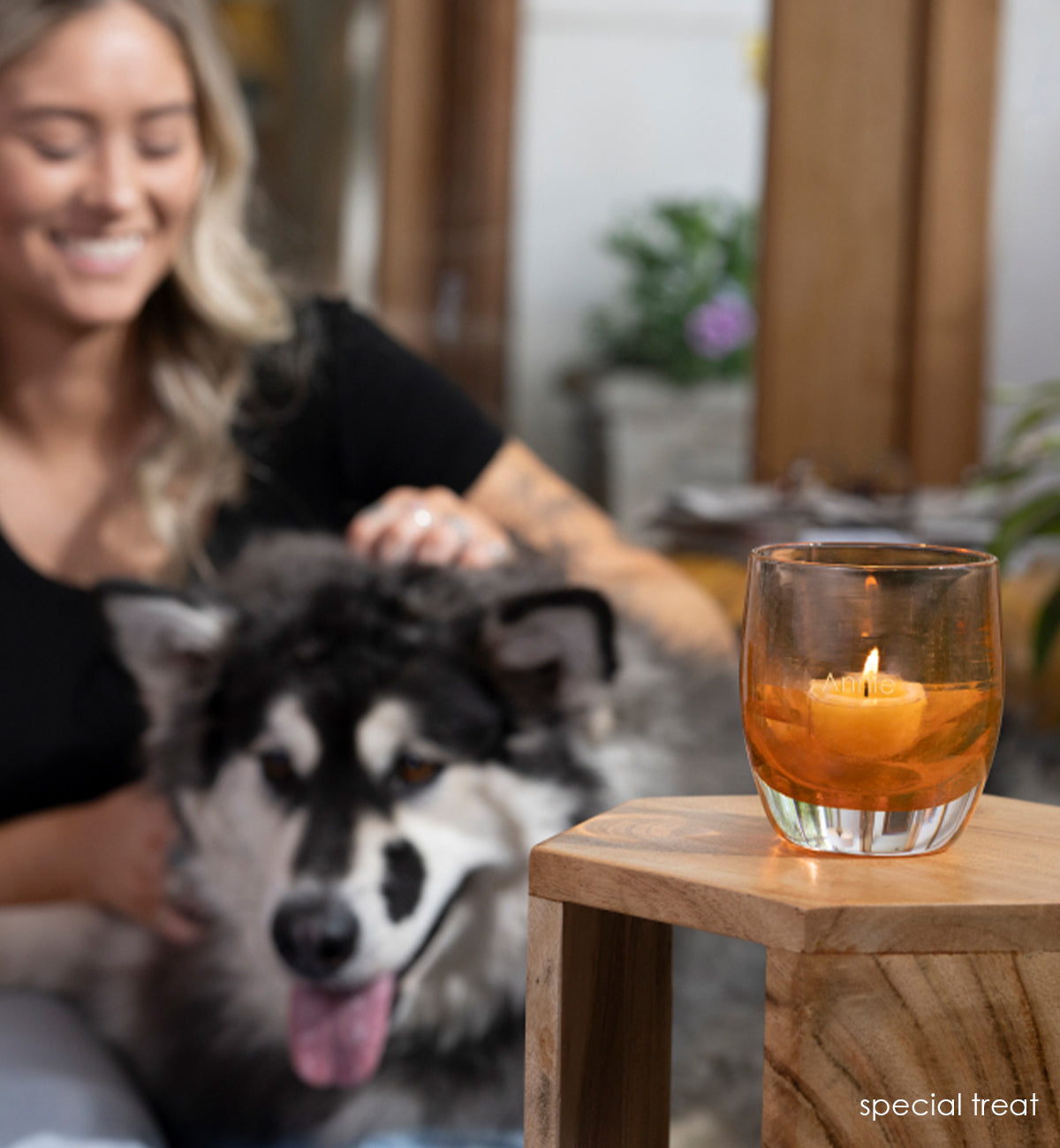 special treat, rustic orange transparent hand-blown glass votive candle holder on a wood stand with Lexi and pup Annie in background.