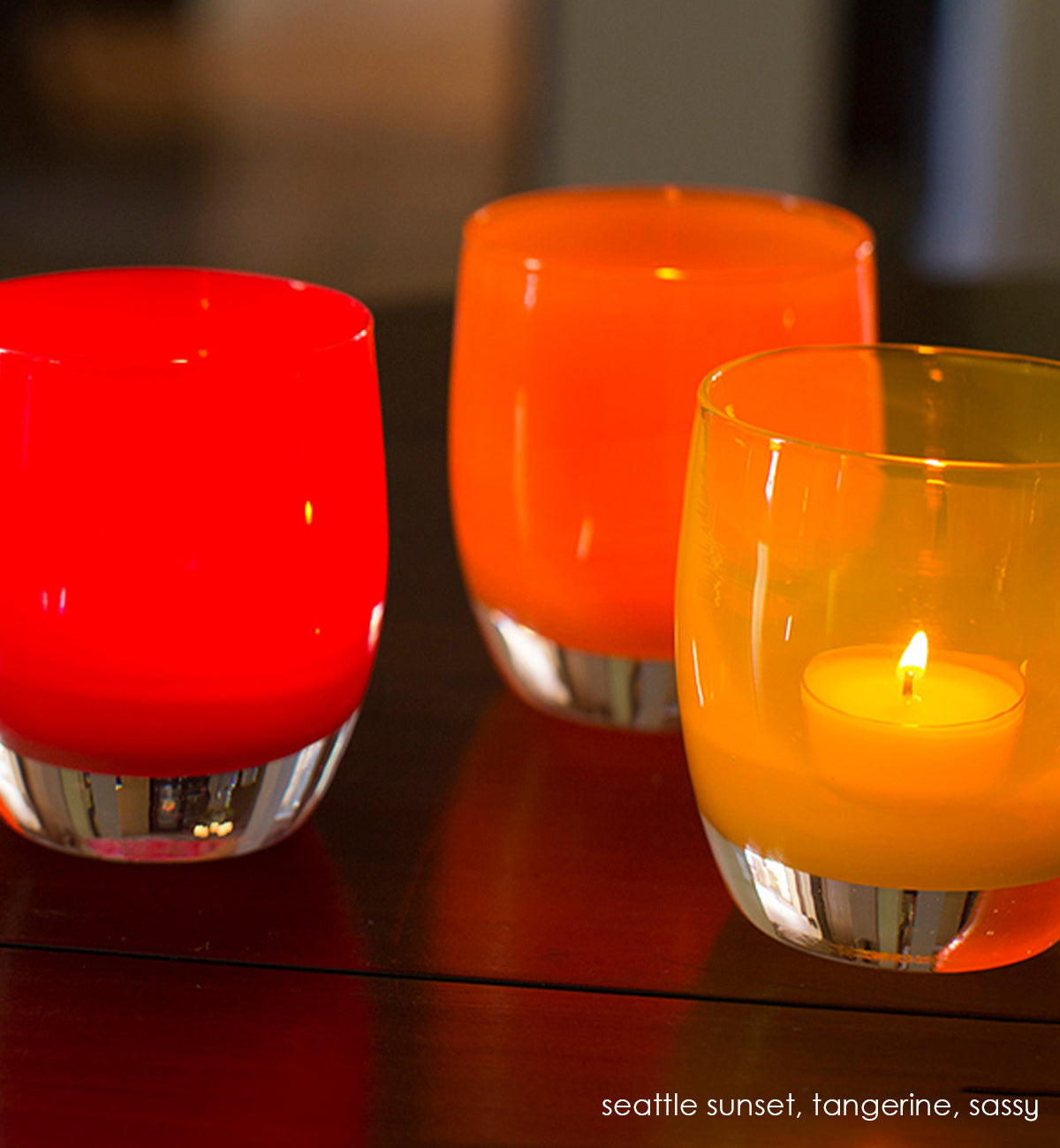 tangerine orange hand-blown glass votive candle holder. Paired with seattle sunset and sassy on a wood table.